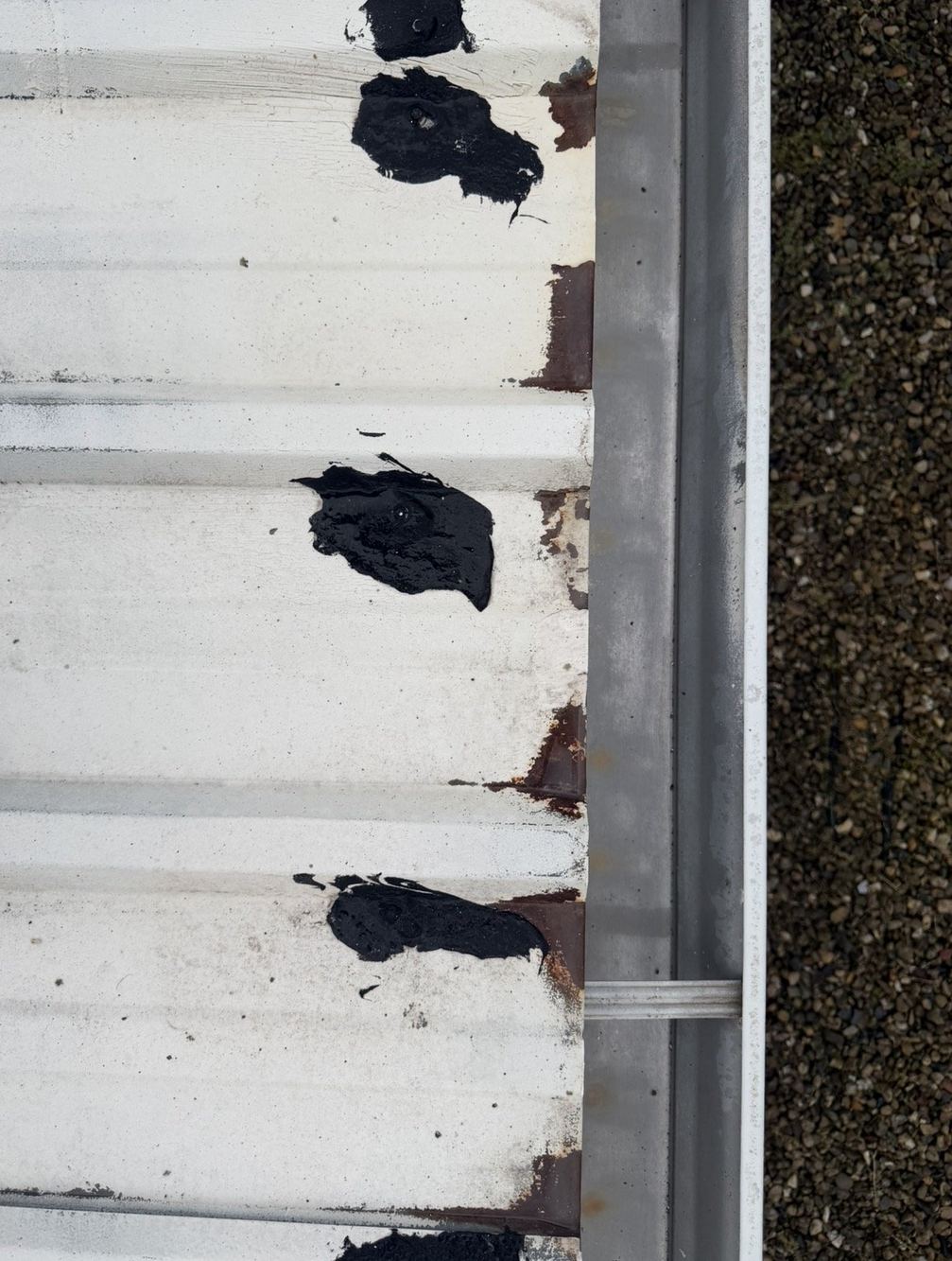 The same gutter run after cleaning, bare metal visible and the channel clear